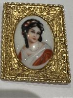 Front view of antique Hattie Carnegie Limoges cameo brooch with detailed gold ornate frame and hand-painted woman portrait.