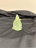 Front view of pale green jade sitting man figurine placed on black fabric