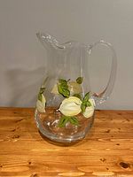 Glass pitcher displayed on wooden table with hand-painted lemon design visible