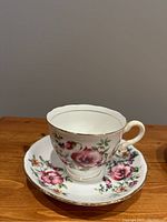 Tea cup and saucer with large purple floral pattern, gold rims, vintage porcelain with slight signs of wear