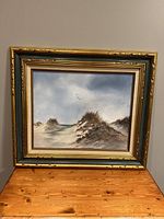Front view of the oil painting showing sand dunes and flying birds framed in ornate gold wood frame