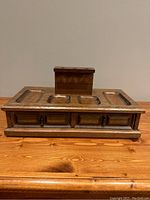 Front view of the vintage men's valet box showing solid wood construction with three drawers and rectangular compartments on top.