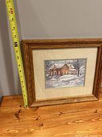 Print in wooden frame with beige matting on wooden surface, measuring tape shows frame height approx 16 inches