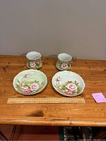 Photo showing the two vintage Lefton cups and matching scalloped edge saucers on a wooden surface with a ruler for scale.
