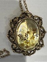 Full view of vintage pendant or brooch with gold tone chain and floral resin dome