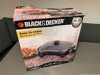 Box showing the front with Black & Decker branding and product image of the 12-inch electric skillet highlighting the easy-to-clean nonstick surface.