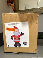 Box showing label with image of Airblown Inflatable Santa decoration. Box is sealed and packed tight, condition new with no size listed.