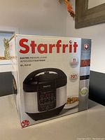 Front and side view of Starfrit electric pressure cooker box showing product image, capacities (8L / 8.5 QT), and brand name.