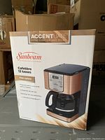 Front view of the Sunbeam coffee maker box showing the product image, copper finish, and features in French.