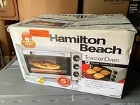 Box of Hamilton Beach toaster oven showing 4-slice capacity and pizza image on front.