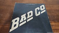Black vinyl album cover with silver diagonal BAD CO lettering, showing wear and scuffs