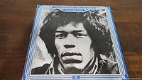 Front cover of The Essential Jimi Hendrix Volume Two vinyl LP showing a black and white photo of Jimi Hendrix on a blue and white background.