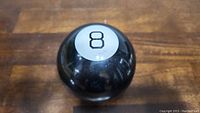 Top view of the Magic 8 Ball showing a silver circle with the number 8 on the surface.