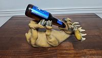Side view of the moose bottle holder with a beer bottle held in its legs and mouth.