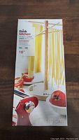 Box showing the Thinkkitchen 16-inch pasta drying rack with pasta hanging to dry