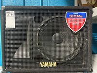 Front view of Yamaha S12Me speaker showing the protective metal grille, woofer, and Yamaha logo badge