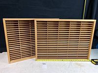 Two Napa Valley wood cassette tape storage boxes side by side against a dark background showing multiple slots and measuring tape indicating length.