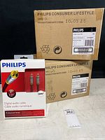 Two brown boxes labeled Philips Consumer Lifestyle, each containing 4 boxed digital audio cables. One box with a visible front package of a Philips digital audio cable shows product details and branding.