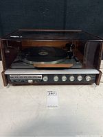 Front view of Benjamin Solid State Stereo 200 with its wooden base and brown plastic dust cover showing the stereo controls and tuning knobs.
