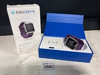 Fitbit Blaze smart fitness watch with purple band inside original blue box with white interior. Outer box shown with product image and features.