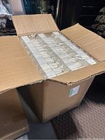 Large cardboard box filled with rows of white ring boxes still in plastic wrapping.