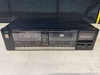 Front view of the MCS Series cassette tape deck player showing two cassette compartments with controls and peak level meter.