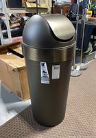Full view of the pewter plastic trash can with lid, showing its size and color.
