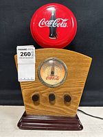 Front view of vintage oak Coca-Cola radio with tri-band control knobs and base.