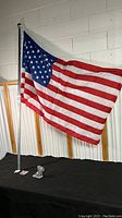 American flag fully extended on pole with black base and bracket shown