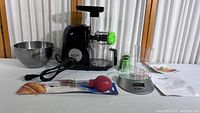 Full view of all items: Aicok slow juicer, mixing bowl, kitchen scale, and silicone baster in packaging on white surface.