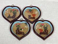 Four heart-shaped shadow box style wall hangings with 3D floral designs and Chinese characters