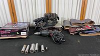 View of Craftsman power tools including drill, belt sander and assorted sockets laid out on table.