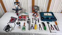 Full view of various tools including staple gun, wrenches, pliers, screwdrivers, tape, pipe wrench, work light and blue carrying case with drill.