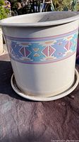 Front view of glazed ceramic planter showing colorful southwestern geometric pattern and built-in saucer with discoloration due to age.