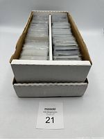 View of the two row cardboard box mostly full with baseball cards sleeved in plastic protectors.