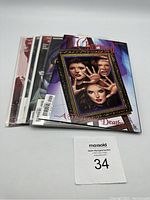 Five Charmed comic books stacked slightly fanned showing one cover clearly with three witches and title 'A Thousand Deaths'