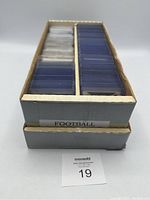 Two-row cardboard box holding football cards in protective sleeves, labeled 'FOOTBALL'.