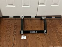 Front view of GOZONE door gym bar placed against a white door showing foam grips and GOZONE branding.