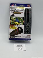 Front view of Bell Howell TacZoom High Performance Zoom Lens in original packaging showing lens and lens holders with 10x zoom feature prominently displayed