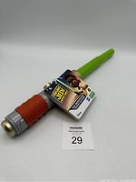 Full view of the Kai Brightstar training lightsaber showing handle and green blade with attached product tag.