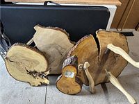 Wood pieces including large slabs with natural bark edges, some with attached wooden handles with metal brackets, and smaller pieces with hooks and other features
