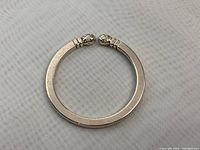 Open circular sterling silver key ring featuring carved acorn ends, laid on light fabric background.