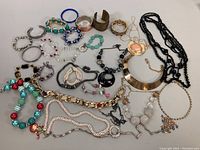 Overview of costume necklaces, bangles, and bracelets laid out together showing variety of styles, colors, and designs.