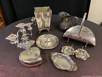 Full view of all items including candelabra, ice bucket, pitcher, dustpan, tray, trinket box, oval dish, and small dishes on dark surface.