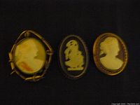 Photo showing all three cameo brooches side by side, highlighting the black Wedgwood brooch in the center and two profile portrait cameos on sides