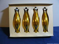 Four gold glass taper shaped Christmas ornaments inside original storage box with individual slots for each ornament.