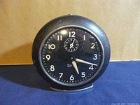 Front view of the Westclox Baby Ben clock showing black dial with white numbers and hands, including small alarm dialing.