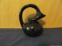 Front angle view of the black ceramic honey pot shaped like a bird with high glossy finish.
