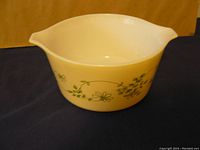 Photo showing side view of round Pyrex casserole dish with green floral pattern on yellow glass.