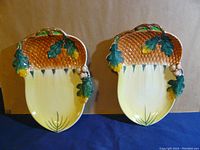 Two acorn-shaped china plates with autumn leaf and acorn decorations shown side by side against a plain background.